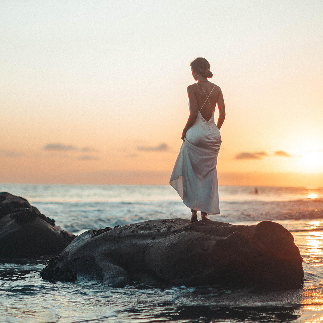 Modellbild på kvinna bakifrån med uppsatt hår mot solnedgången
